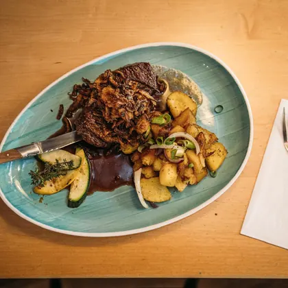 Krustenbraten mit Kartoffeln auf türkisfarbenem Teller