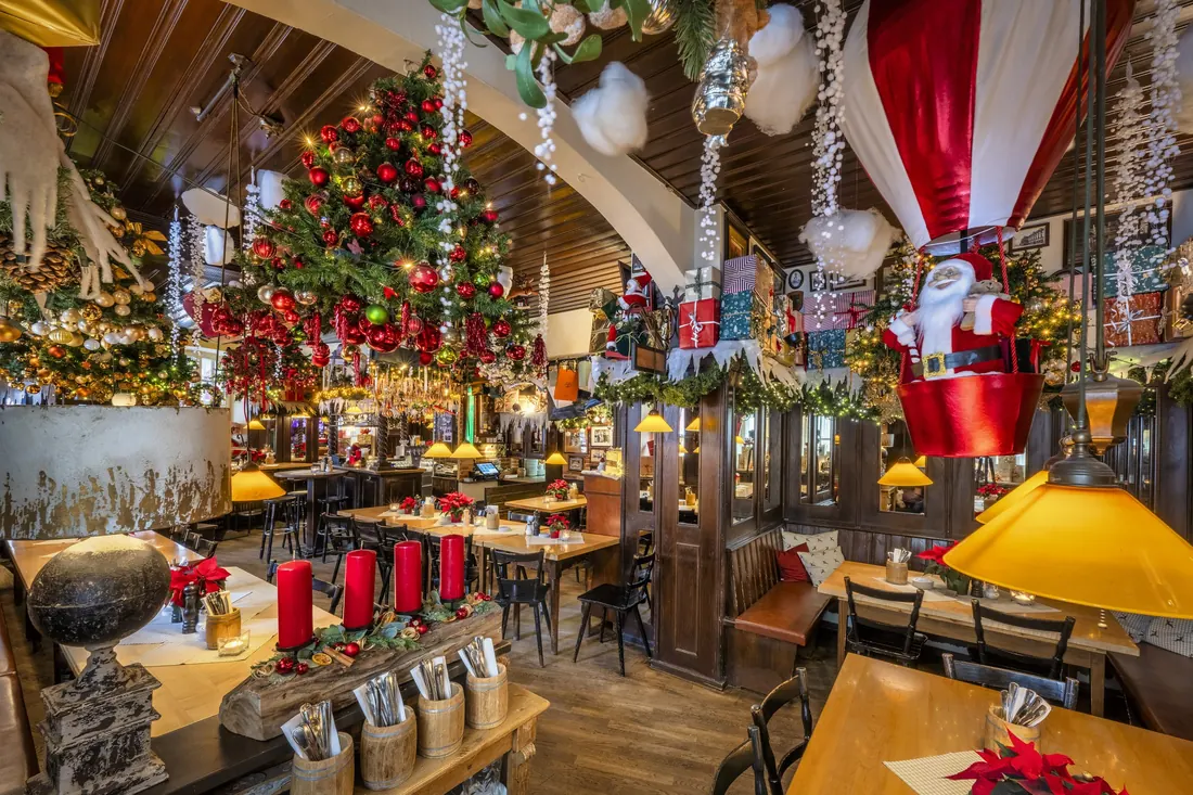 Weihnachtlich geschmückte Gaststube mit Christbaum und roten Kerzen